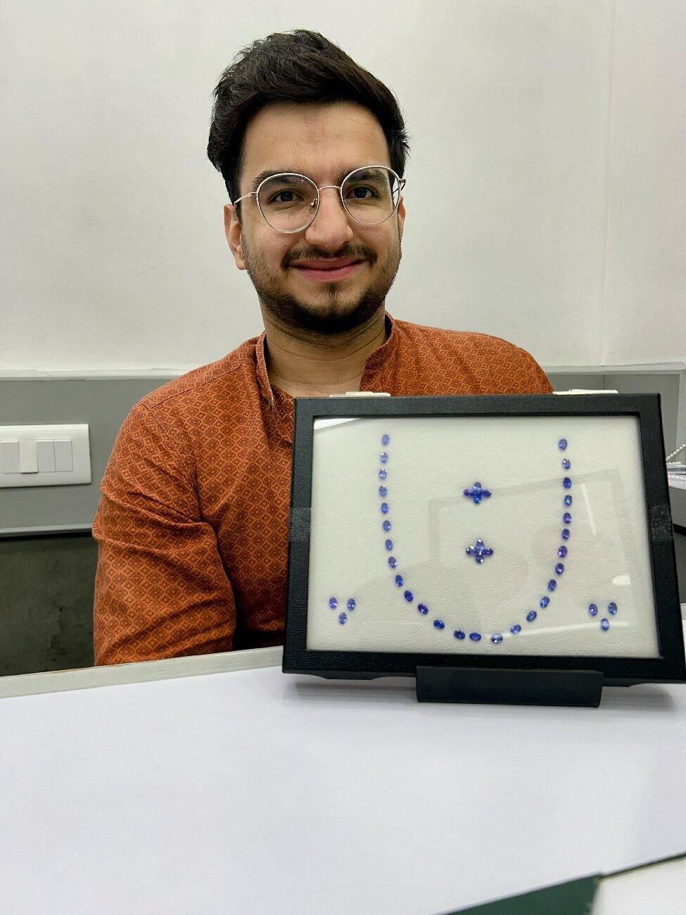 A person with glasses behind a framed display of blue gemstones in a photo attached to Vivek’s Tripadvisor review